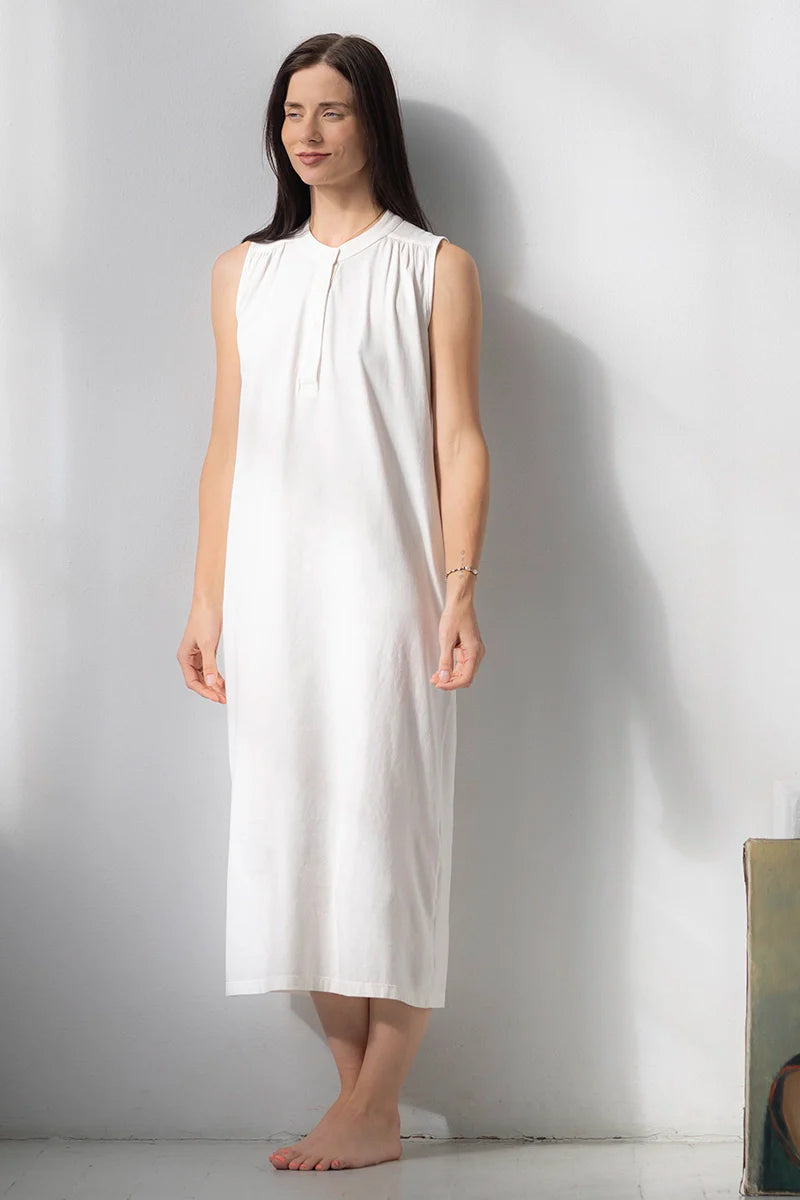Woman wearing a white sleeveless dress against a plain background