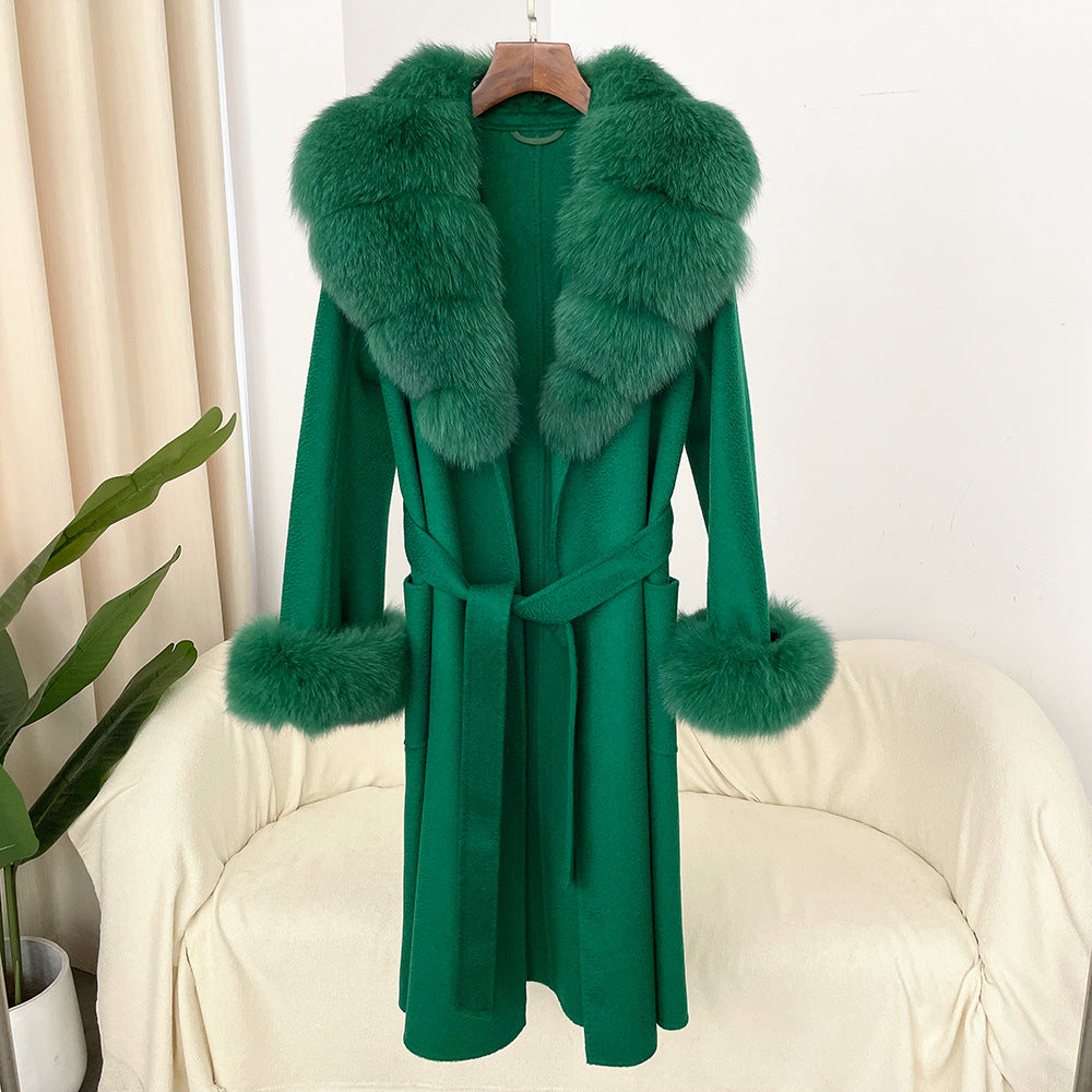 Green coat with fur trim on a hanger against a white background
