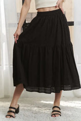 Person wearing a black tiered skirt with lace trim on a neutral background