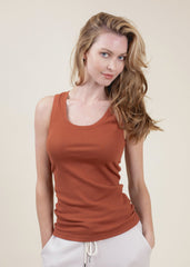 Woman wearing a rust-colored tank top against a beige background