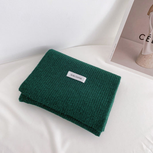 Green folded blanket with a label on a white surface