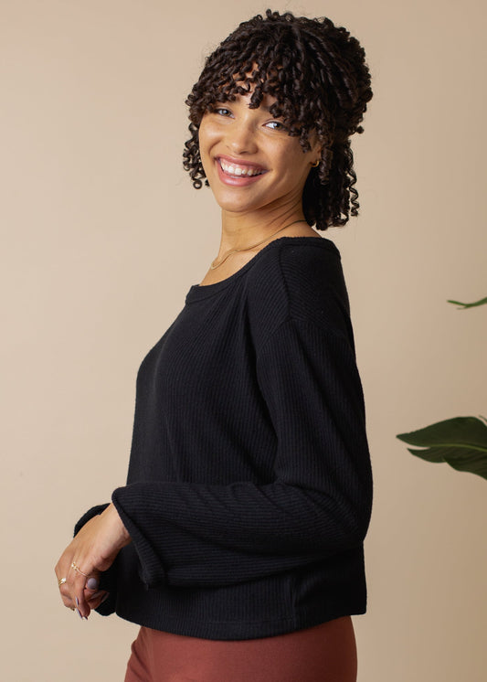 Woman wearing a black sweater against a beige background