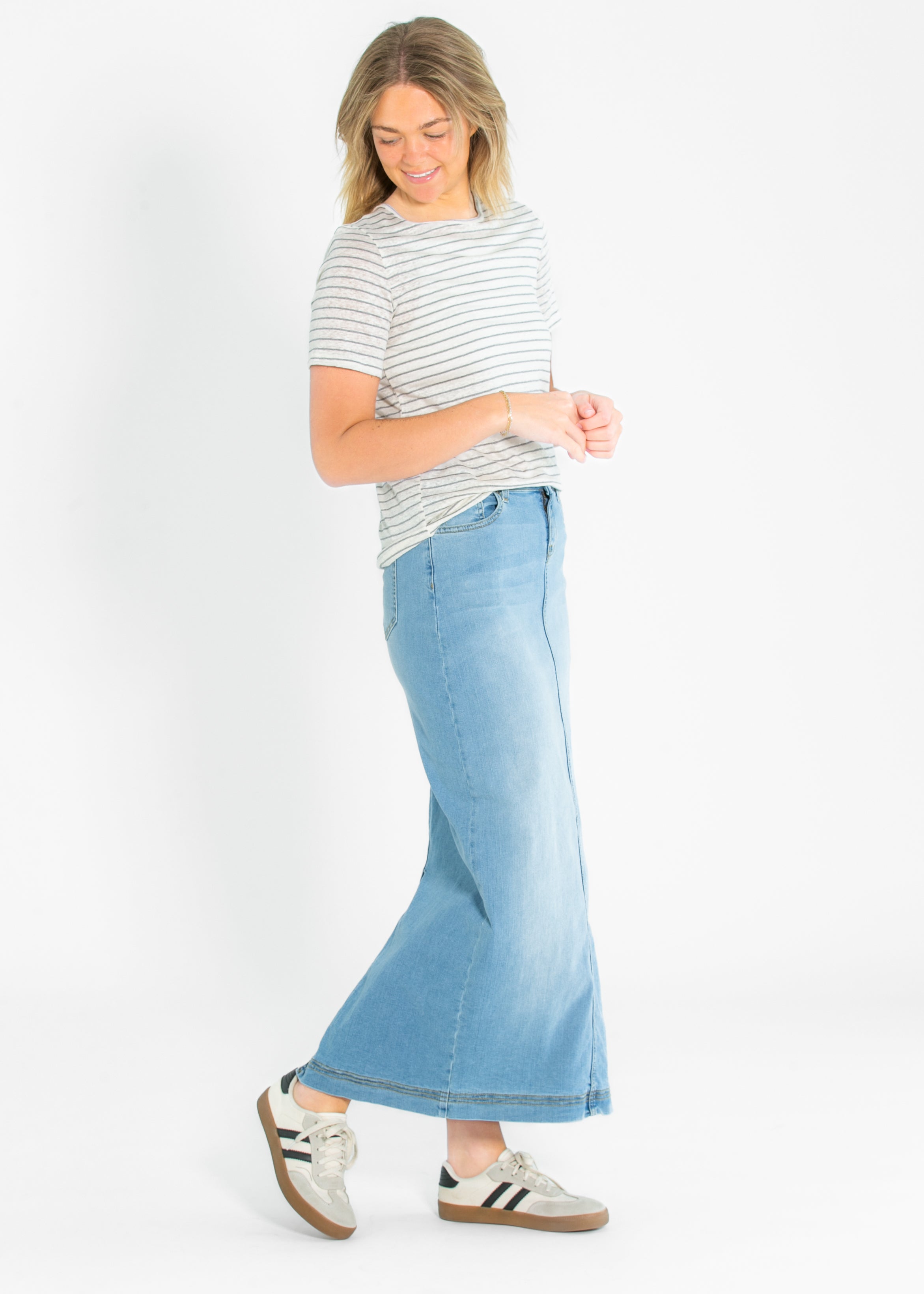 Woman wearing a striped shirt and light blue jeans on a white background
