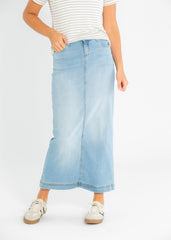 Person wearing a light blue denim skirt with a white background