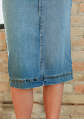Close-up of a blue denim skirt against a brick wall background