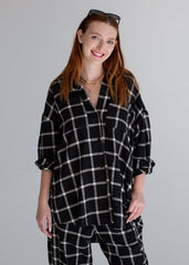 Woman wearing a black and white checkered shirt and pants against a gray background