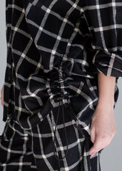 Black and white checkered dress with a ruched waist on a plain background