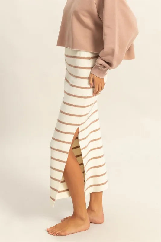 Person wearing a beige and brown striped skirt on a plain background