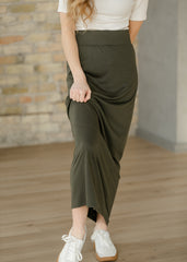 Person wearing a green skirt and white top against a brick wall.