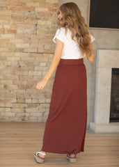 Woman wearing a white top and red skirt standing in a room with a stone wall and fireplace.