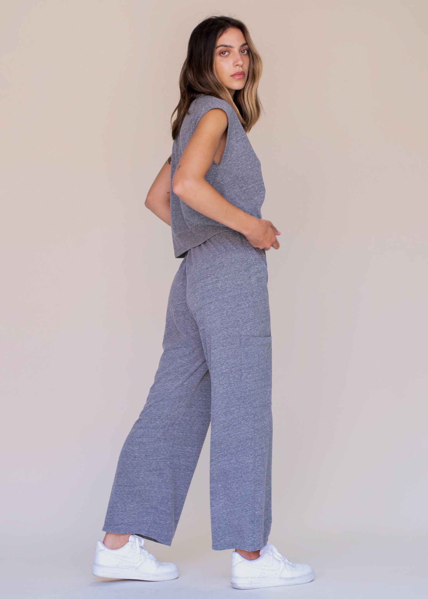 Woman wearing a gray sleeveless top and wide-leg pants against a beige background