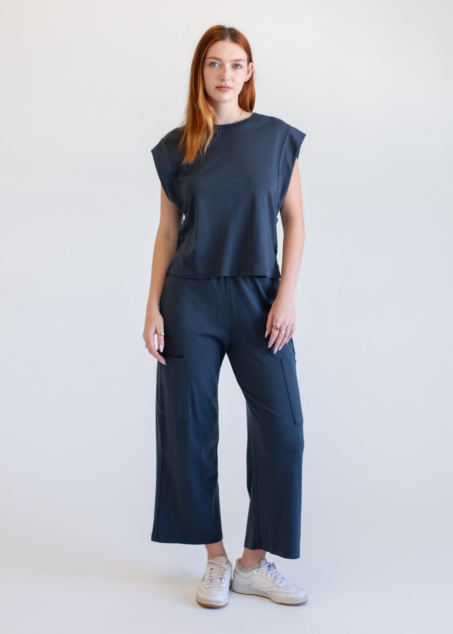 Woman wearing a navy blue outfit with a top and pants on a white background