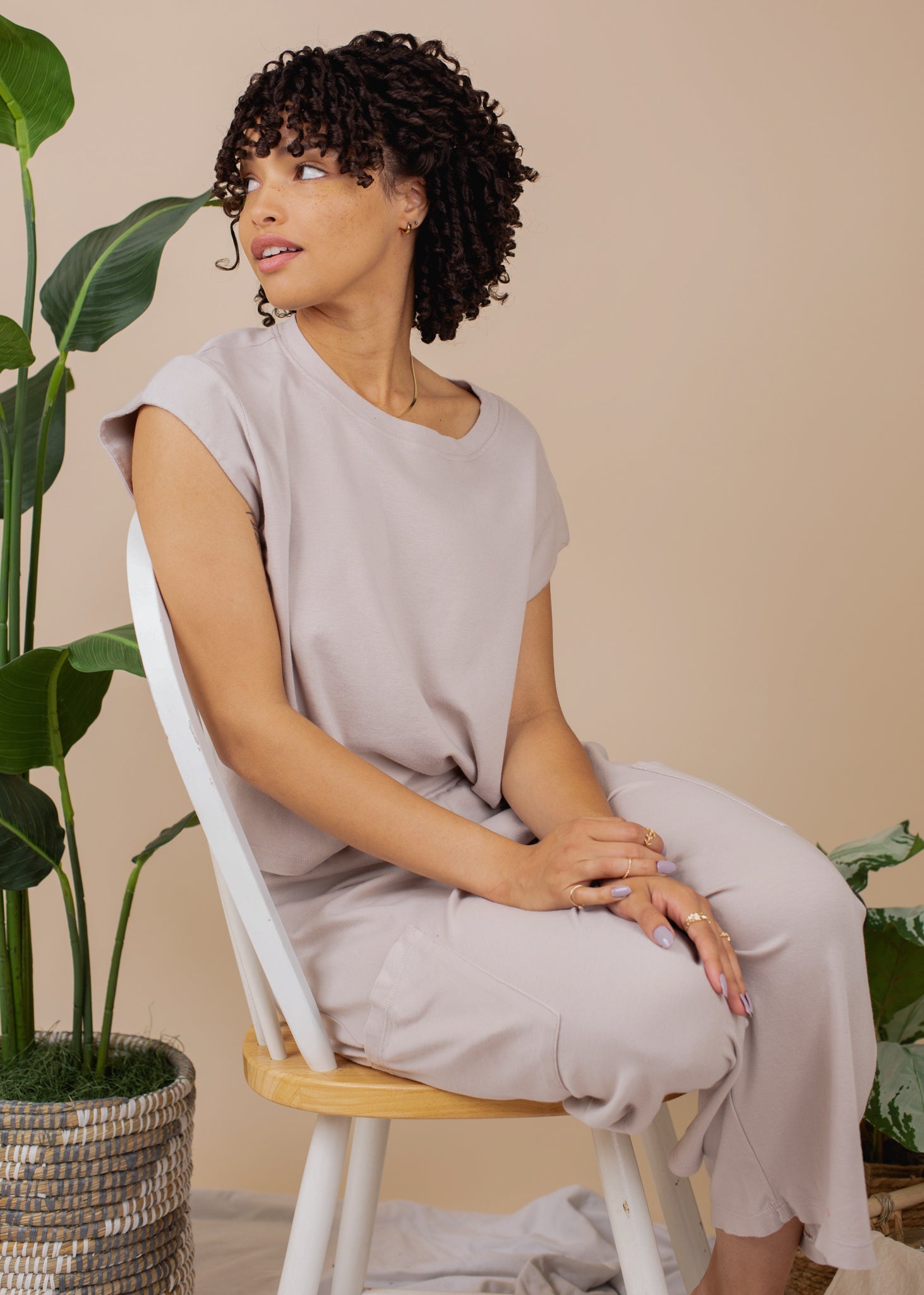Woman sitting on a chair in a neutral setting with plants