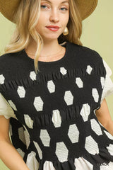 Woman wearing a black and white patterned sleeveless top with a straw hat against a yellow background