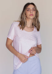 Woman wearing a light pink t-shirt and light blue pants against a plain background