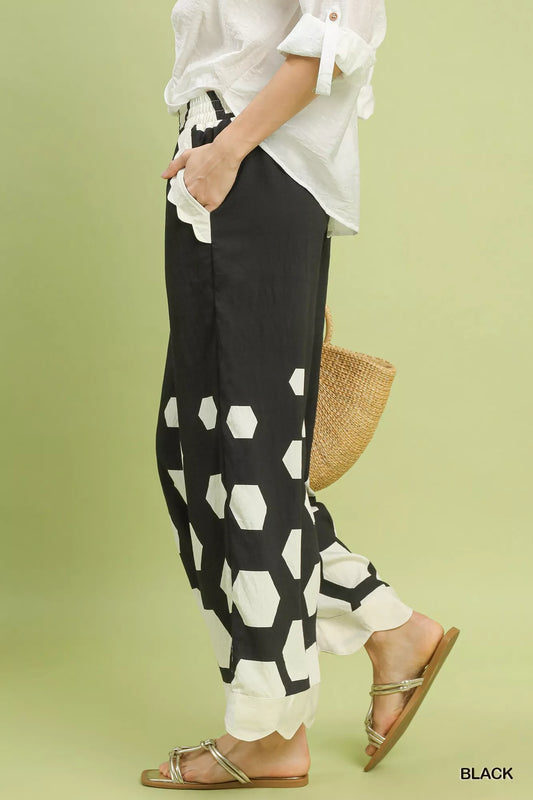 Person wearing black and white patterned pants with a white top on a light green background