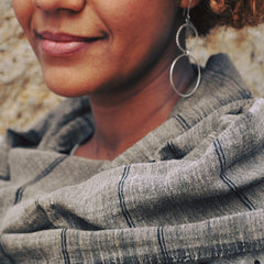 Close-up of a person wearing a gray scarf with a blurred natural background