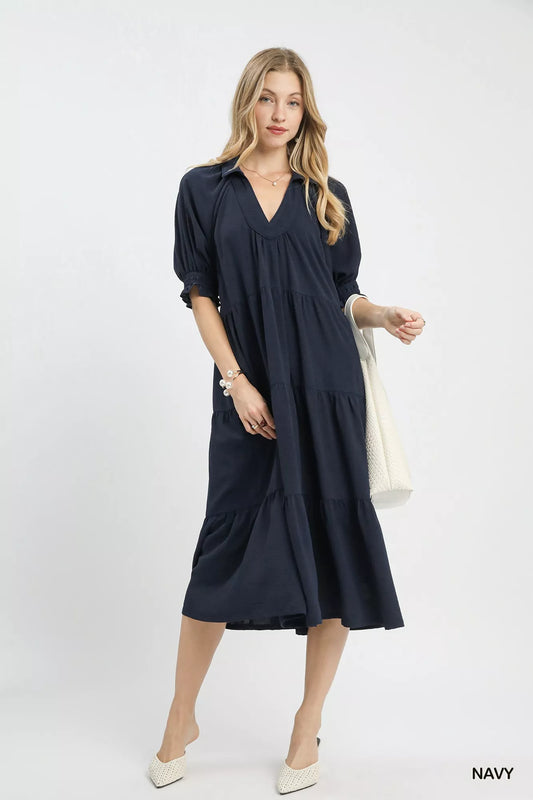 Woman wearing a navy dress holding a white bag on a white background