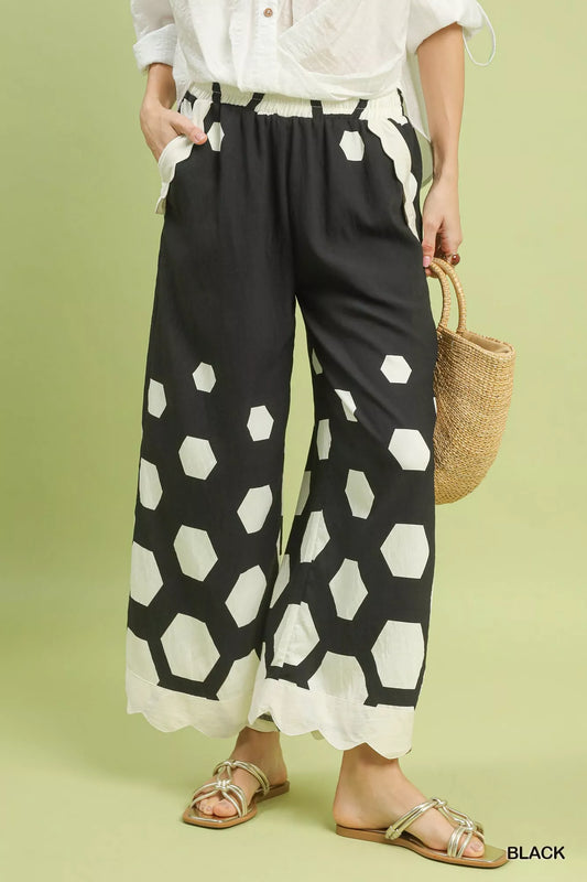 Person wearing black and white patterned pants with a white top on a green background