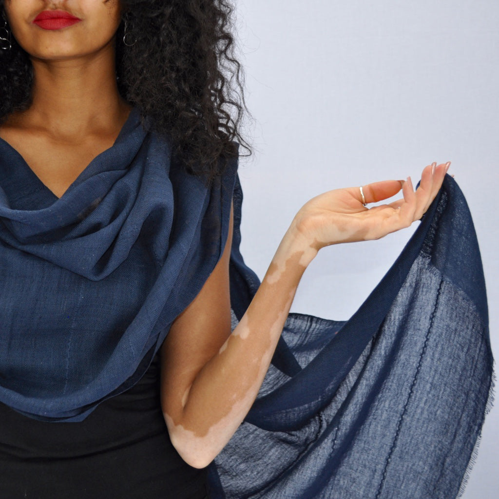 Woman holding a blue scarf against a light gray background