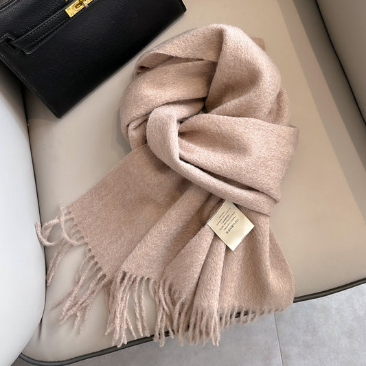 Beige scarf with a tag on a white surface next to a black handbag