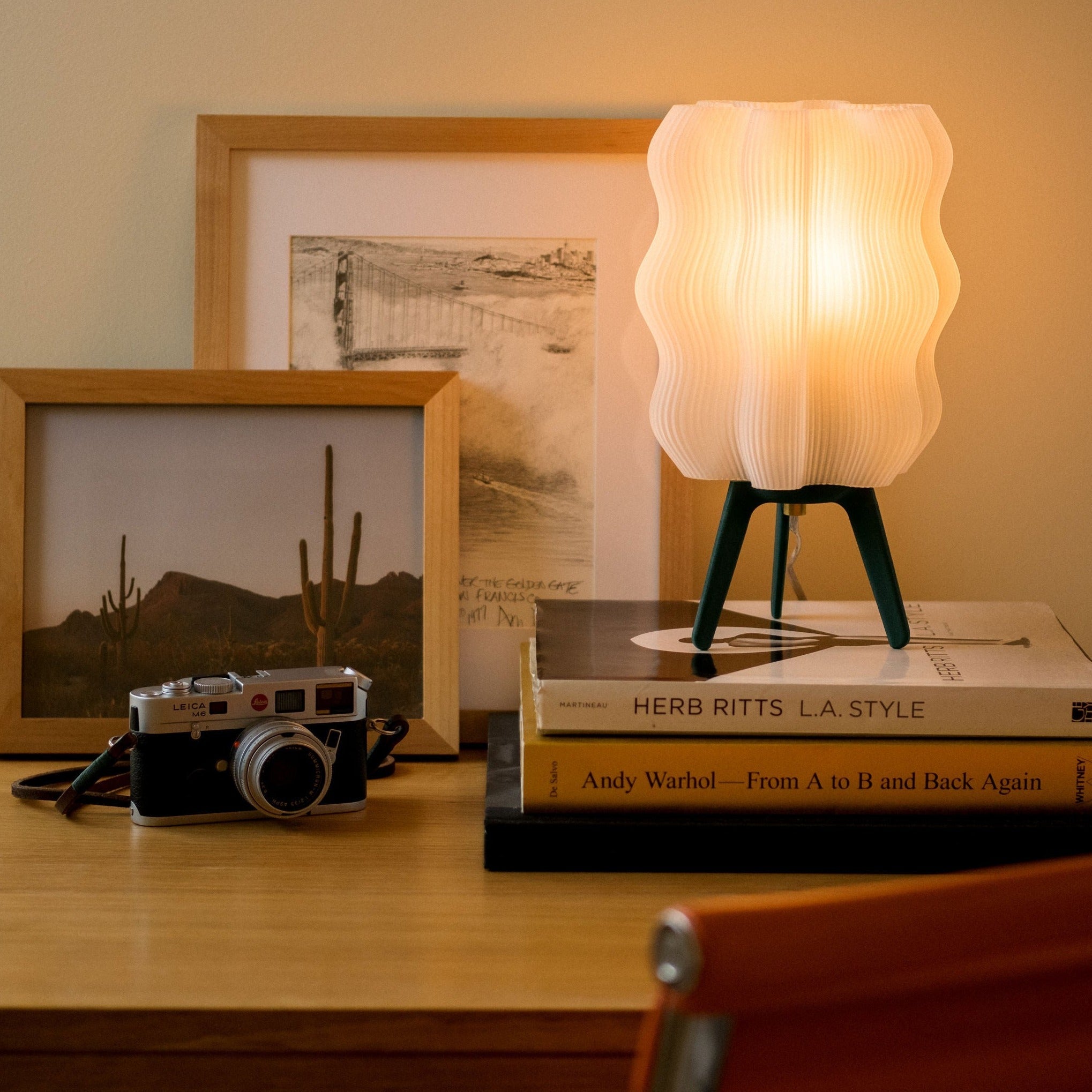 Small lamp on books with a camera and framed pictures in the background