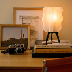 Small lamp on books with a camera and framed pictures in the background