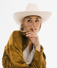Woman wearing a white hat and brown suede jacket with fringes on a white background