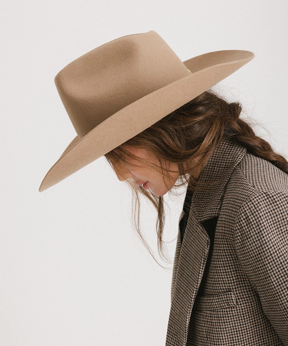 Person wearing a beige hat and checkered coat on a white background