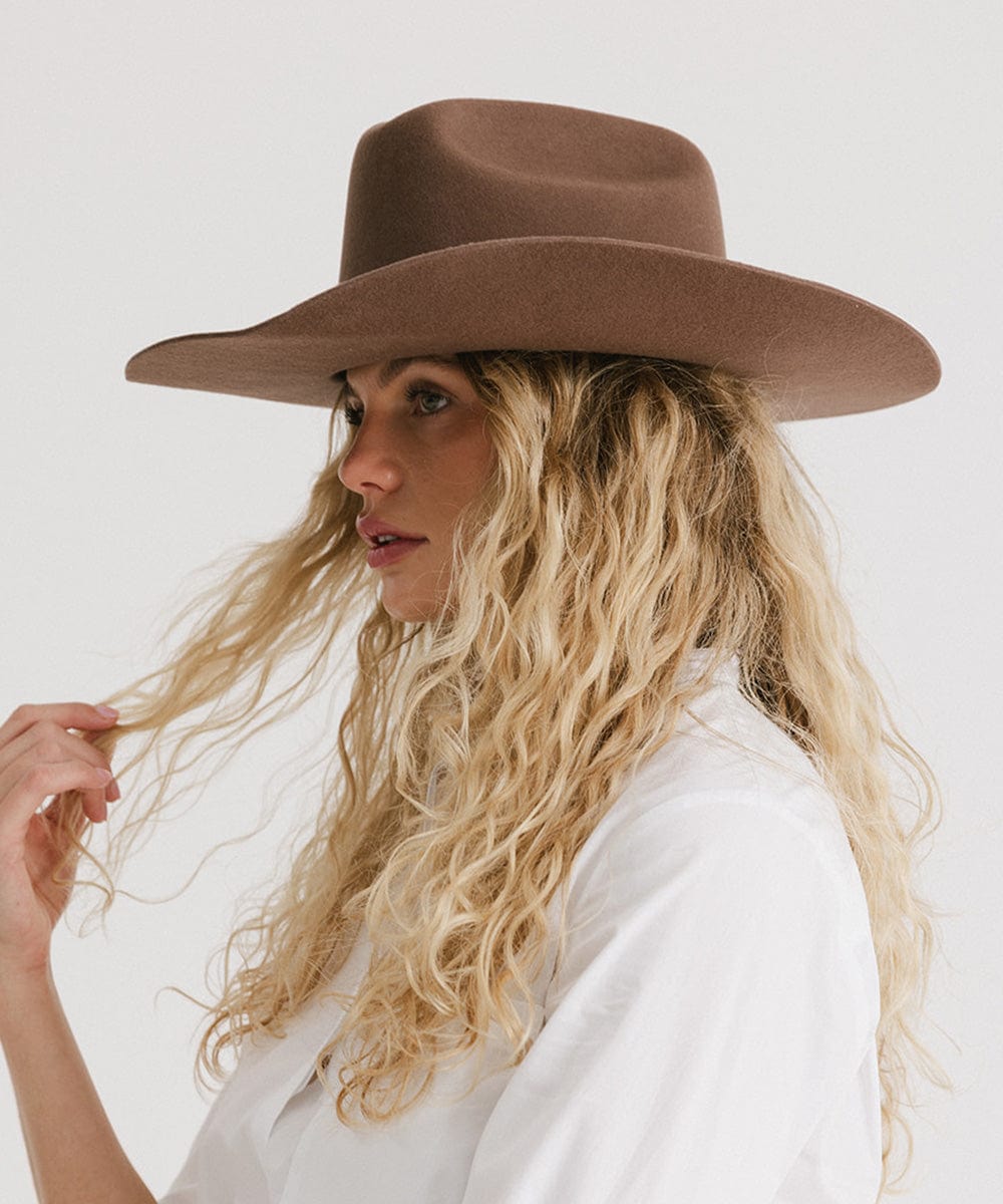 Woman wearing a brown wide-brimmed hat against a white background