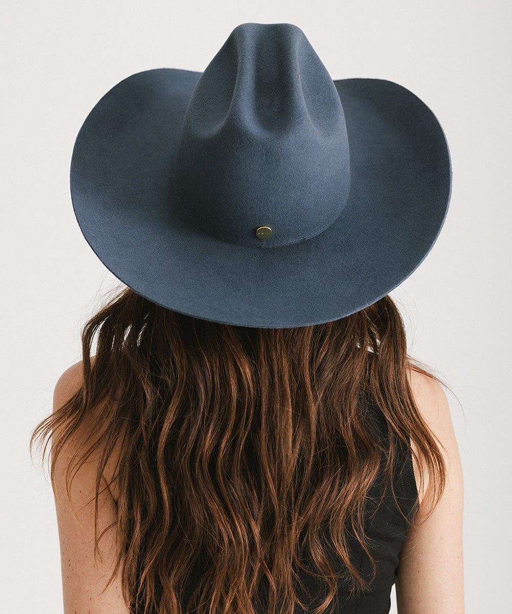 Person wearing a blue fedora hat with a plain background