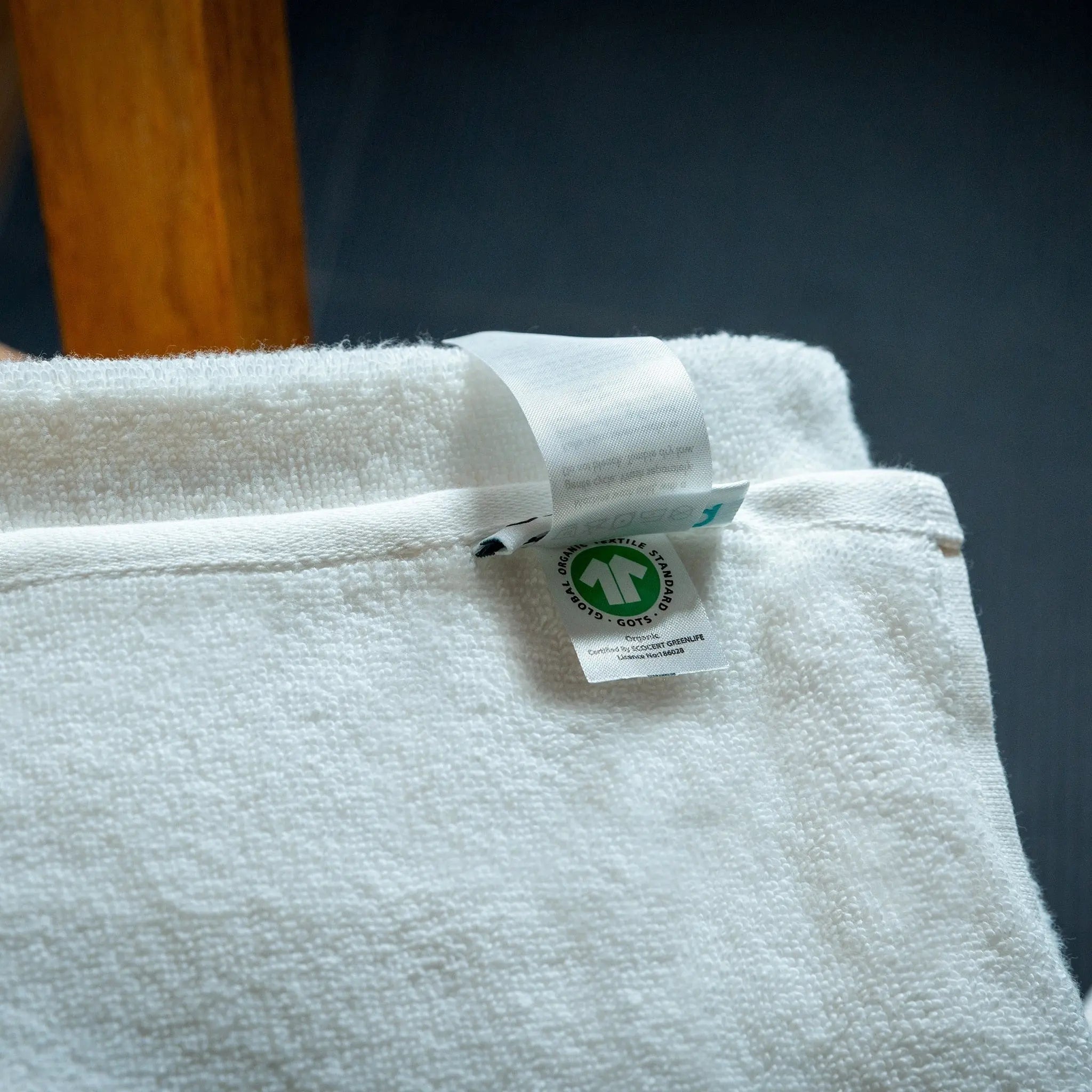 Close-up of a white fabric with a green label on a dark background