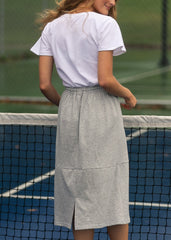 Person wearing a white t-shirt and gray skirt on a tennis court