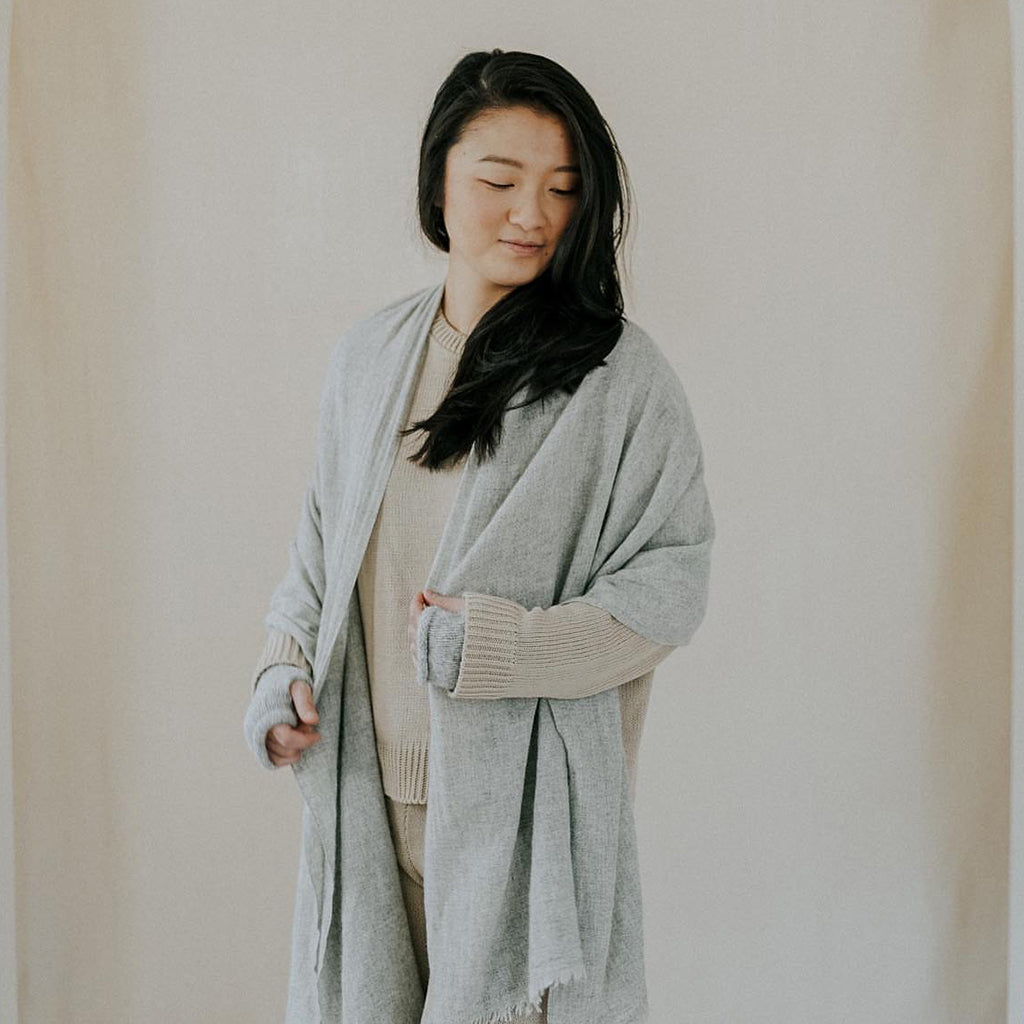 Woman wearing a gray cardigan against a plain background