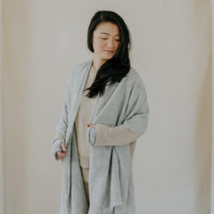 Woman wearing a gray cardigan against a plain background