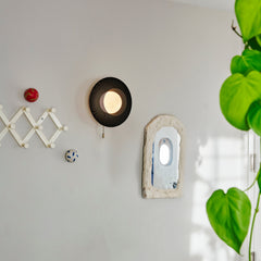 Decorative wall items including a round black lamp, small mirror, and decorative balls on a light gray wall.