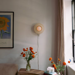 Living room with a wall lamp, flowers in vases, and a sunflower painting.
