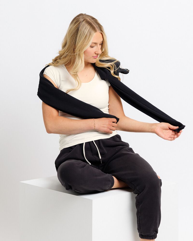 Woman using a black shoulder massager on a white background