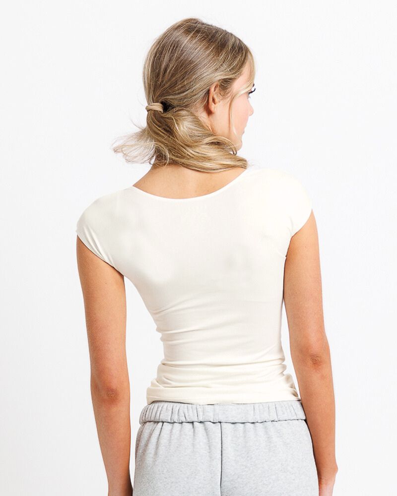 Woman wearing a white t-shirt and gray pants on a plain background