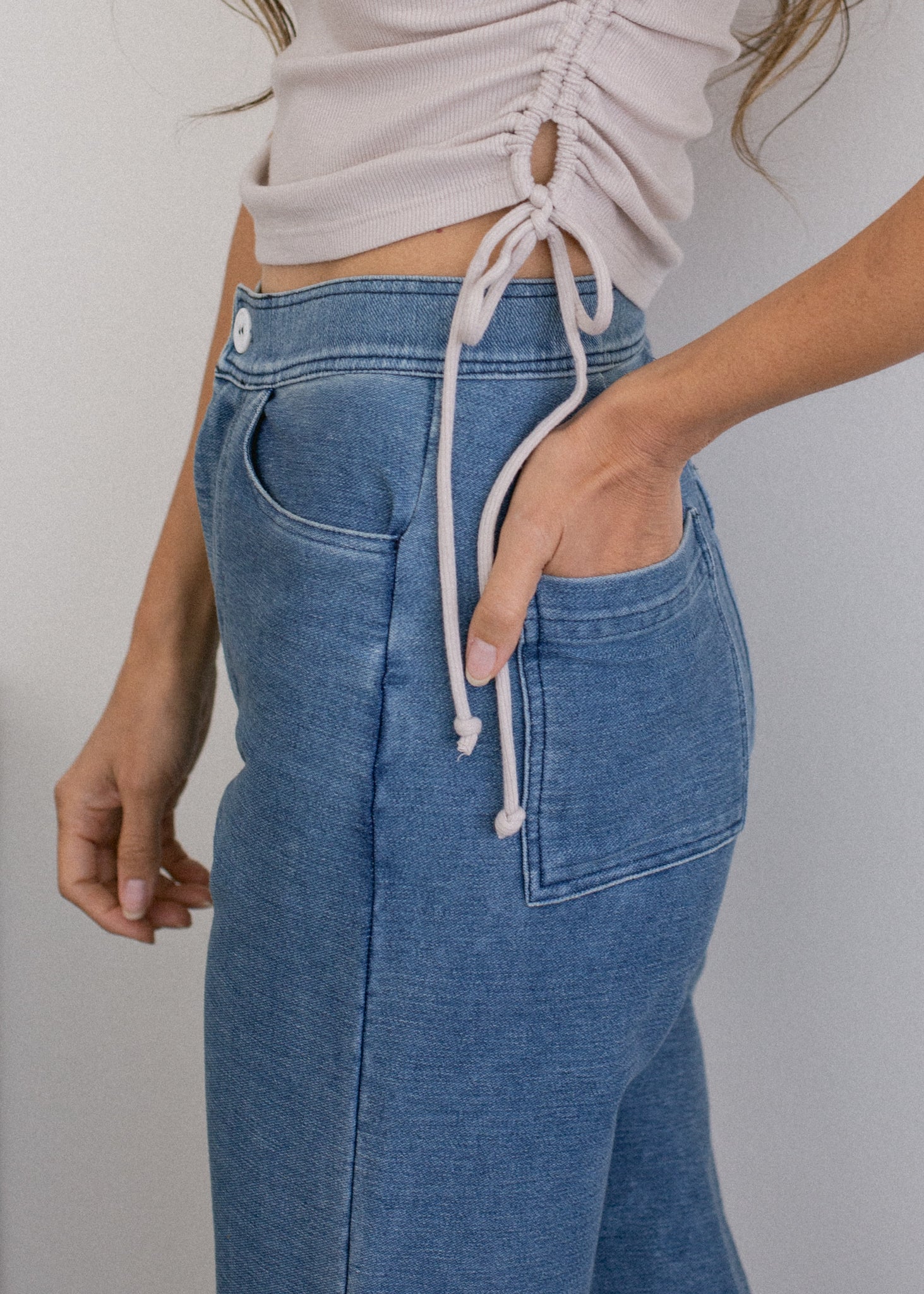 Blue jeans with a white drawstring worn by a person on a plain background