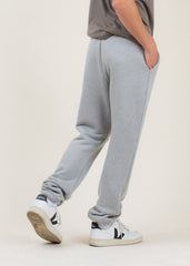 Person wearing gray sweatpants and white sneakers on a plain background