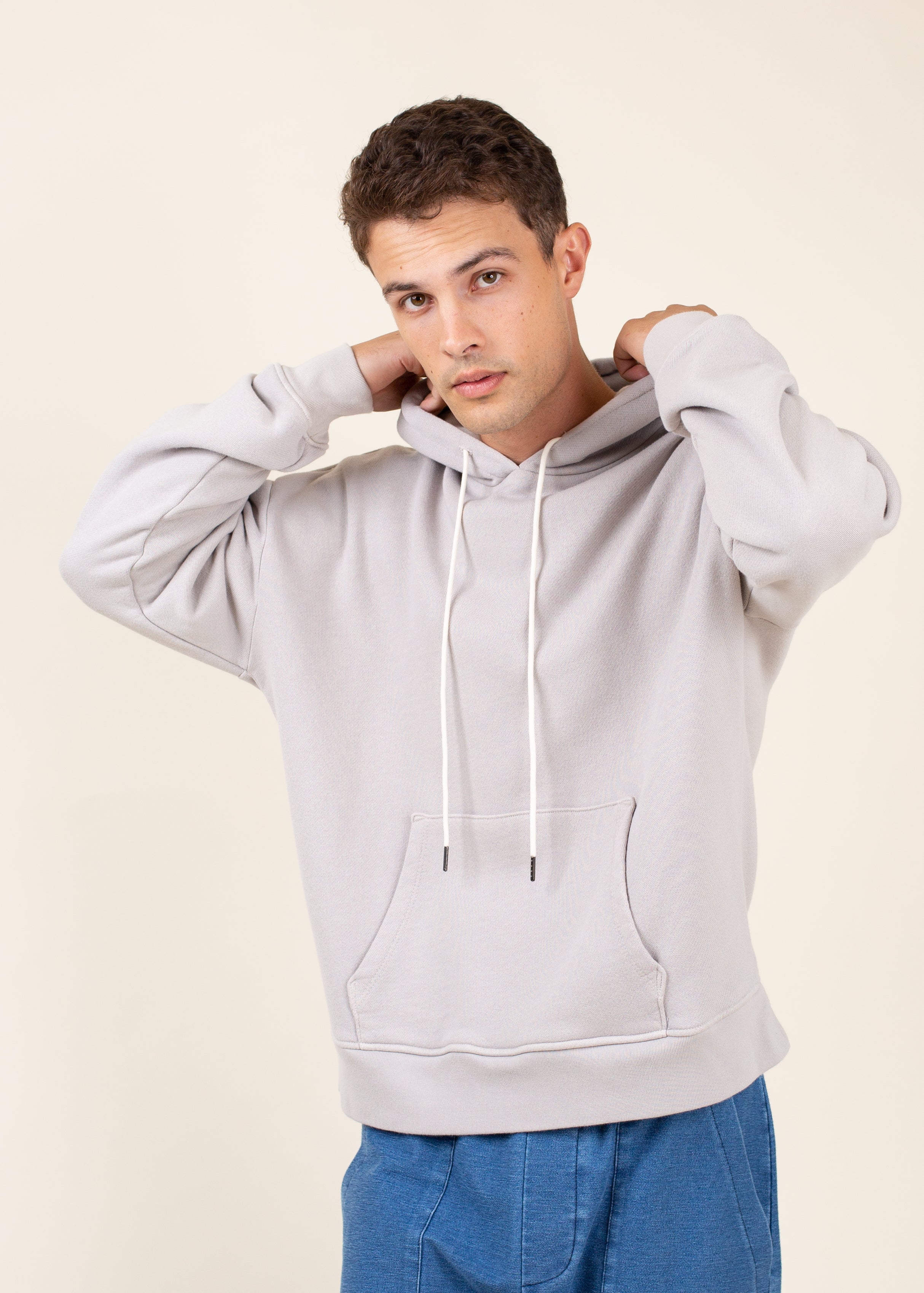 Man wearing a light gray hoodie against a beige background