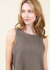 Woman wearing a brown sleeveless top against a plain background