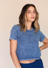 Woman wearing a blue acid-wash t-shirt against a beige background