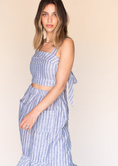 Woman wearing a blue and white striped dress against a beige background