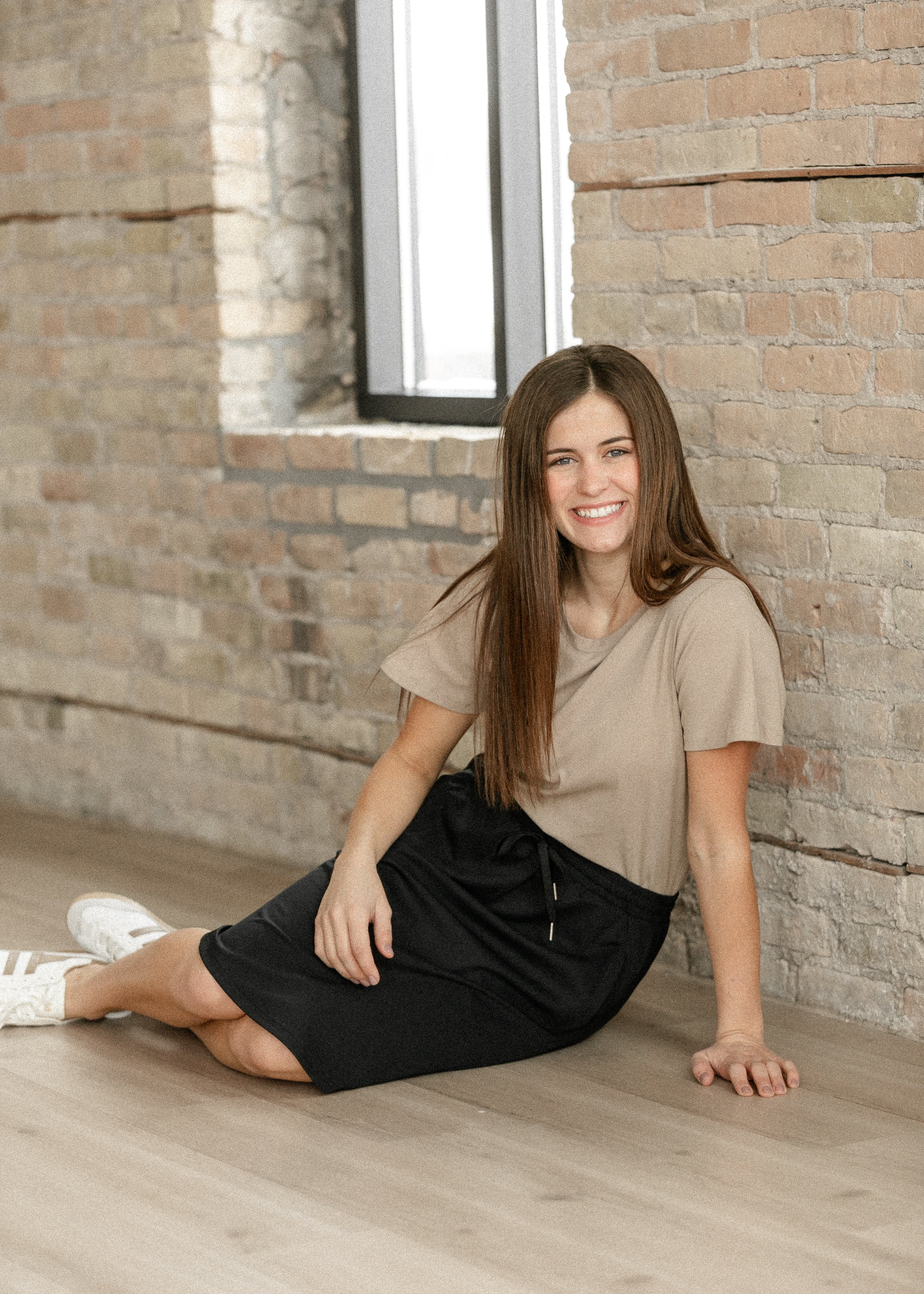 Woman sitting on the floor against a brick wall