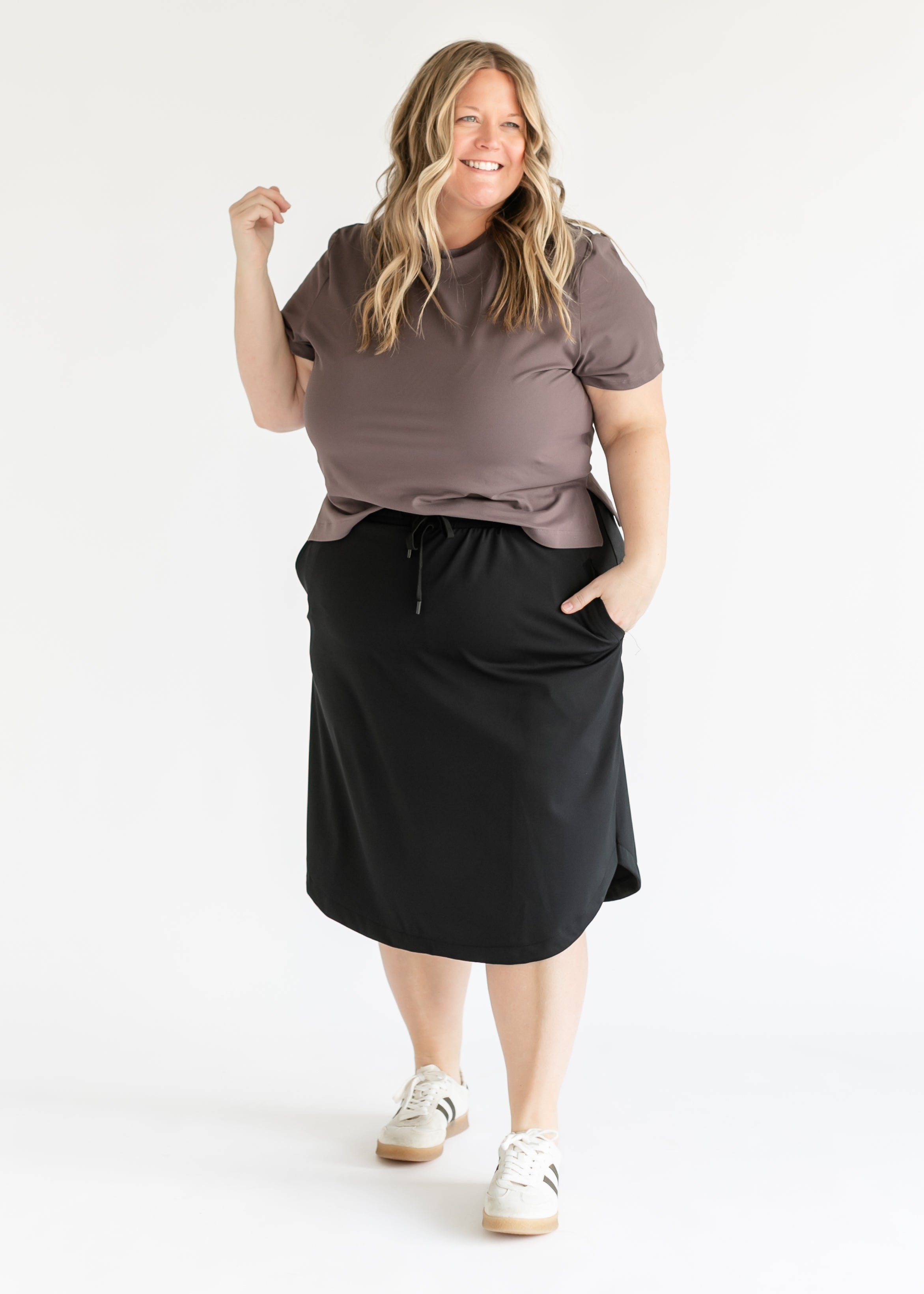 Woman wearing a brown top and black skirt on a white background