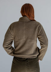 Person wearing a brown fleece jacket against a gray background