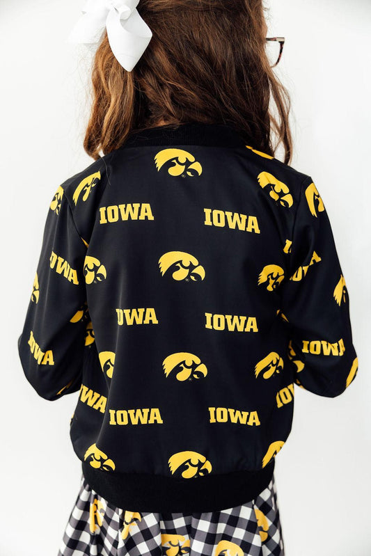 Black jacket with yellow 'Iowa' text and logos on a person against a white background