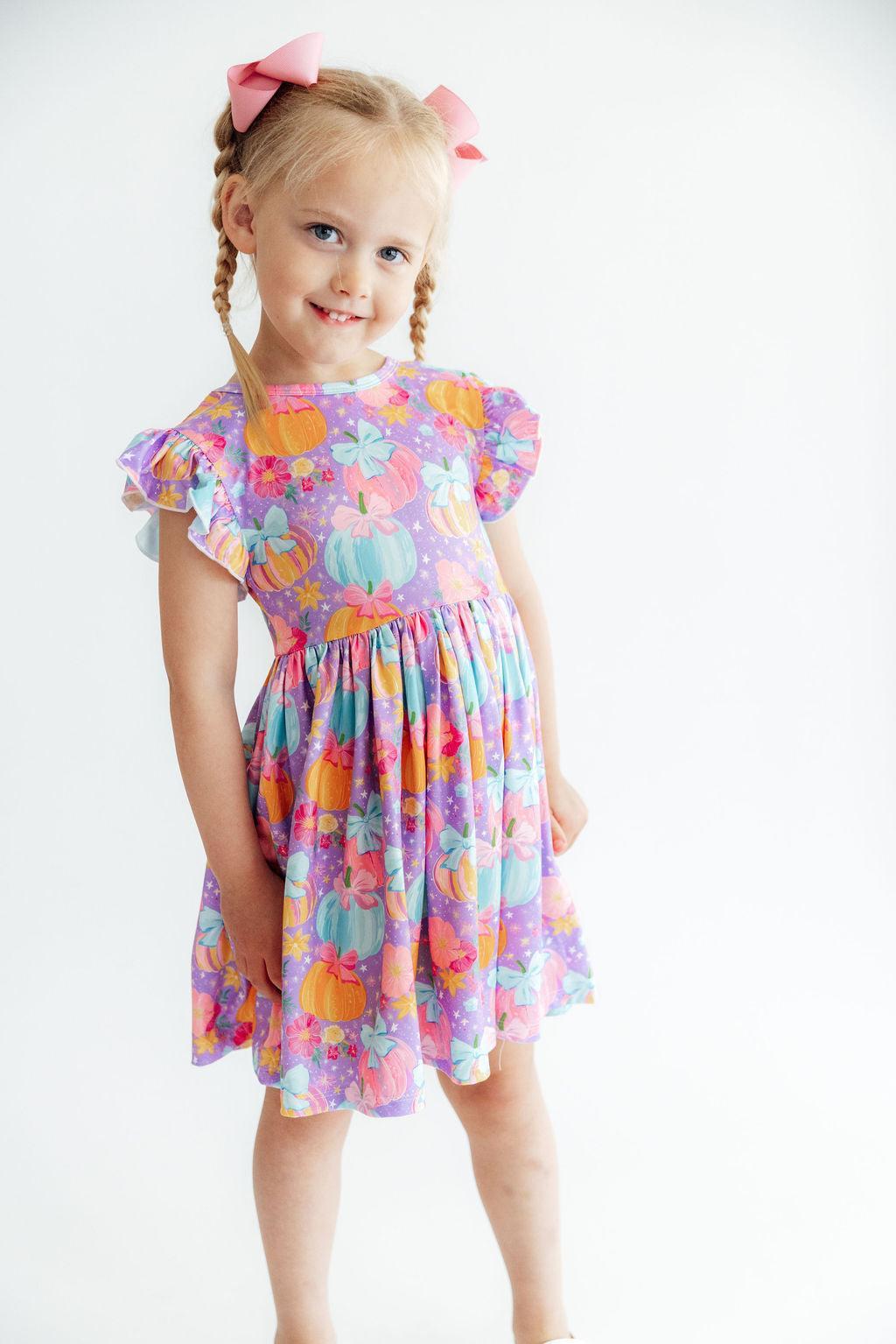 Young girl wearing a colorful floral dress on a white background